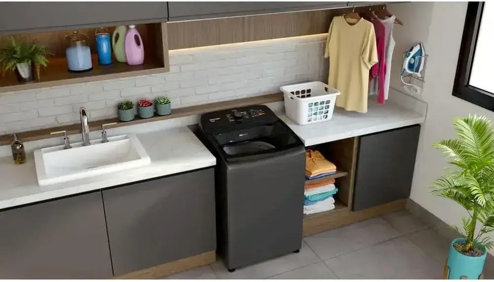 imagem lateral da máquina de lavar, com cozinha ao fundo e parede de tijolos brancos.