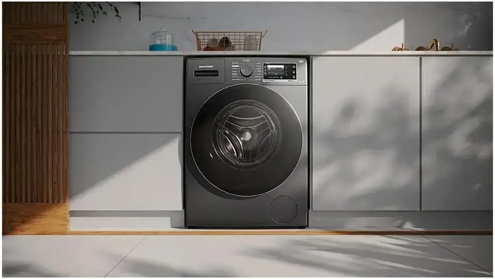 Máquina de lavar em uma cozinha com armários brancos e uma bancada de madeira clara.